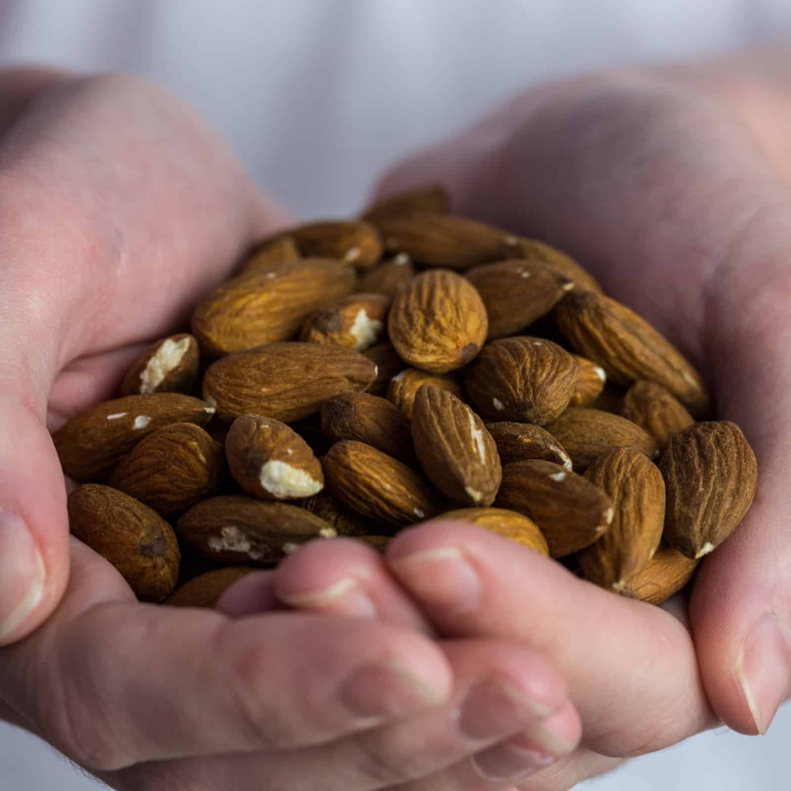 Woman showing handful of almonds in close up